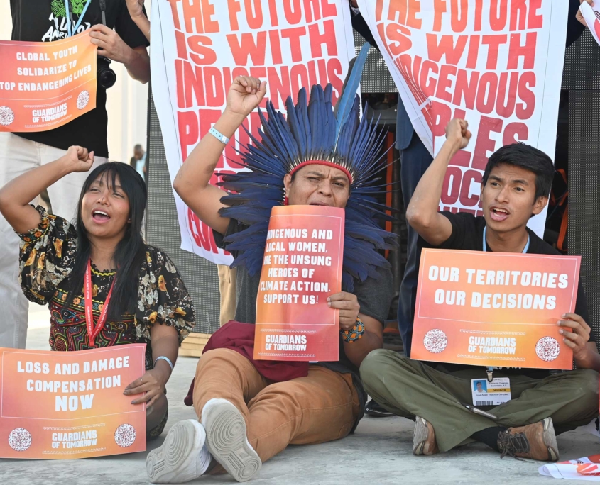 activistas climáticos jóvenes levantan puños y sostienen carteles en defensa de los derechos de los indígenas y la acción por el clima en la COP28