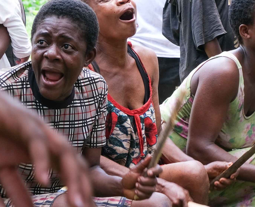 group of people enthusiastically playing drums and chanting during a communal gathering in Cameroon, expressing emotion and energy