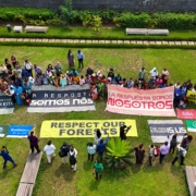 aerial view of diverse group on grass holding banners calling for forest protection and climate justice