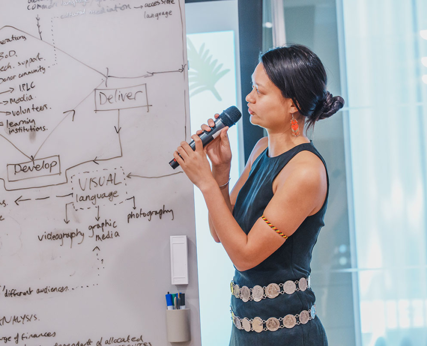 indigenous woman speaking looking at diagram on whiteboard